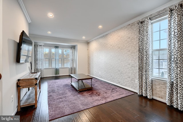 unfurnished living room featuring baseboards, dark wood finished floors, brick wall, ornamental molding, and recessed lighting