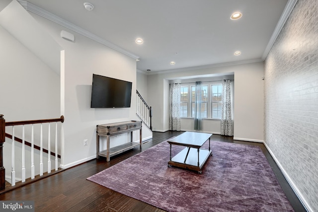 living area with baseboards, dark wood-style floors, brick wall, stairway, and crown molding