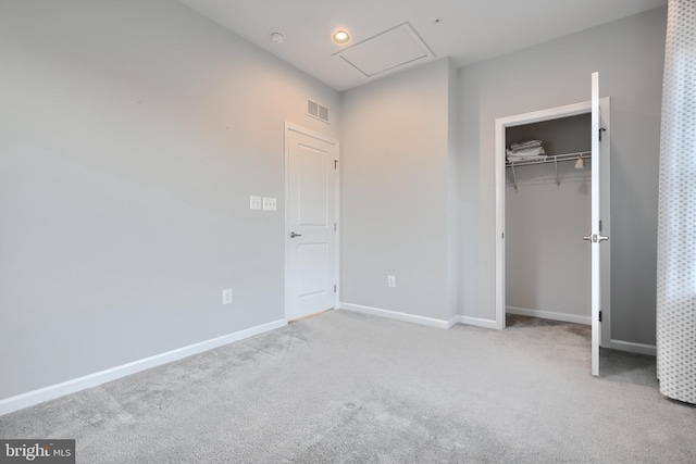 unfurnished bedroom with light carpet, visible vents, baseboards, a closet, and attic access