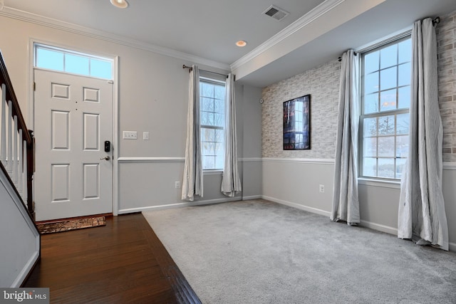 entryway with crown molding, visible vents, plenty of natural light, and baseboards