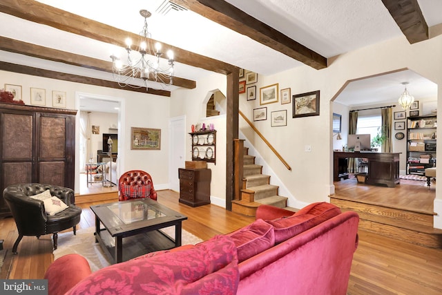 living room featuring visible vents, wood finished floors, a notable chandelier, stairs, and beam ceiling