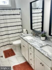 bathroom with tile patterned floors, a sink, toilet, and double vanity