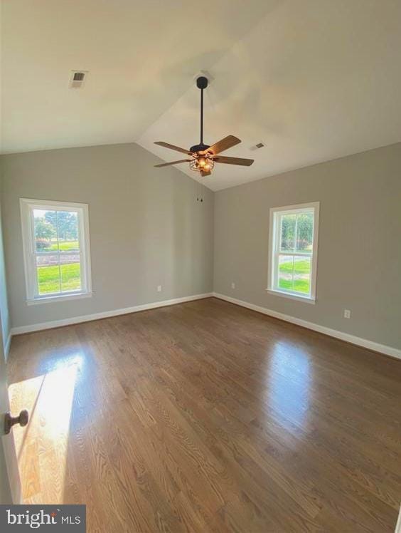 unfurnished room featuring vaulted ceiling, a wealth of natural light, wood finished floors, and visible vents