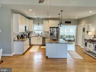 kitchen featuring a kitchen island, white cabinetry, stainless steel appliances, and pendant lighting