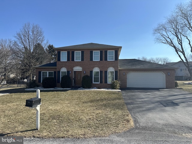 view of front of property featuring aphalt driveway, a front lawn, brick siding, and an attached garage