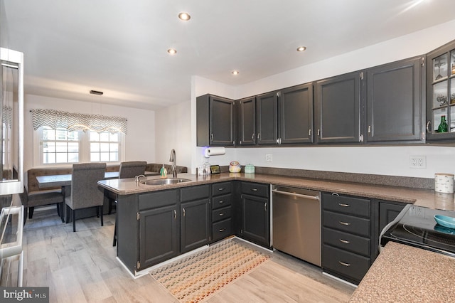 kitchen with light wood finished floors, recessed lighting, a peninsula, stainless steel dishwasher, and a sink