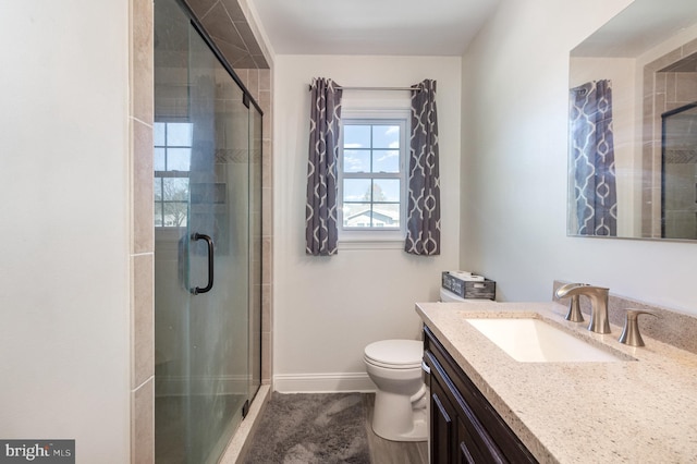 full bath with toilet, a stall shower, vanity, and baseboards