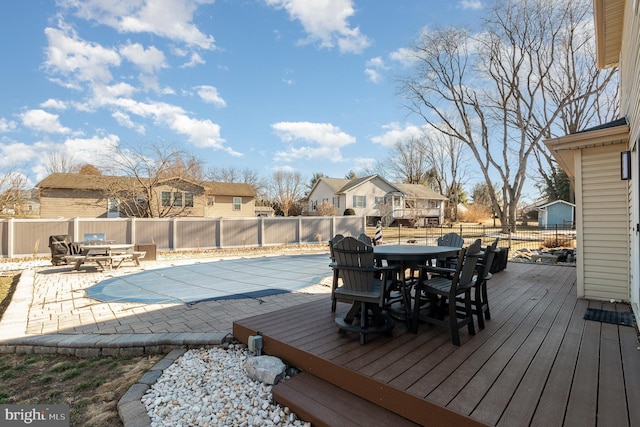 wooden deck with outdoor dining space, a fenced in pool, a residential view, and a fenced backyard