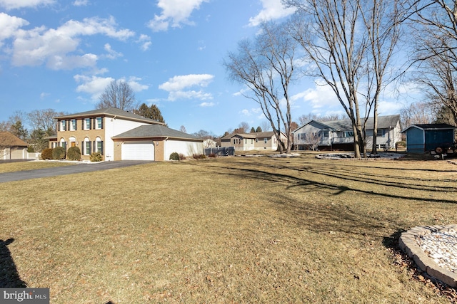 view of yard with aphalt driveway, a garage, and a residential view