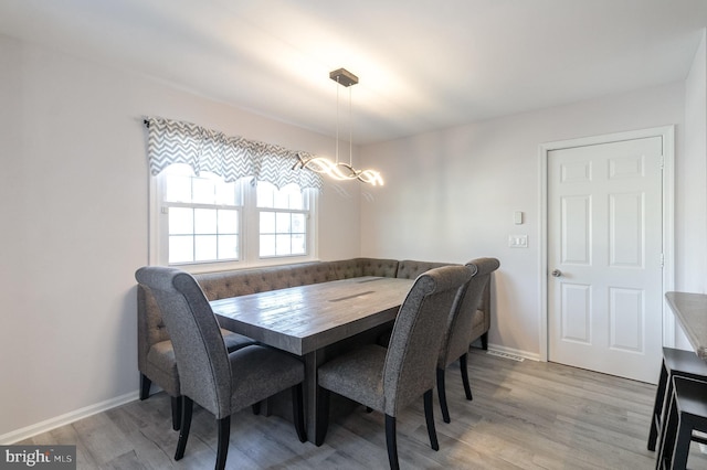 dining area featuring baseboards, light wood-style floors, and a chandelier