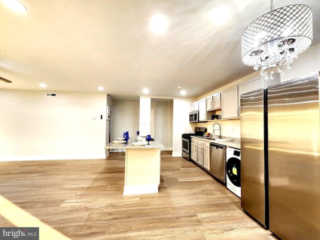 kitchen with recessed lighting, washer / clothes dryer, a sink, appliances with stainless steel finishes, and light wood finished floors