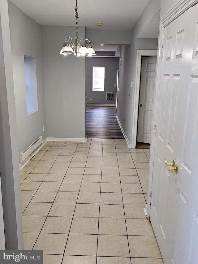 interior space featuring light tile patterned floors, a baseboard radiator, a notable chandelier, visible vents, and baseboards