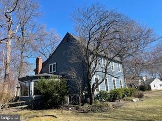 view of home's exterior featuring a chimney and a sunroom