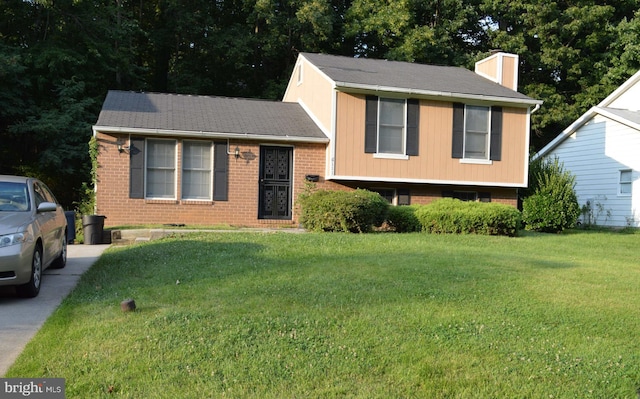 tri-level home with a front yard, a chimney, and brick siding