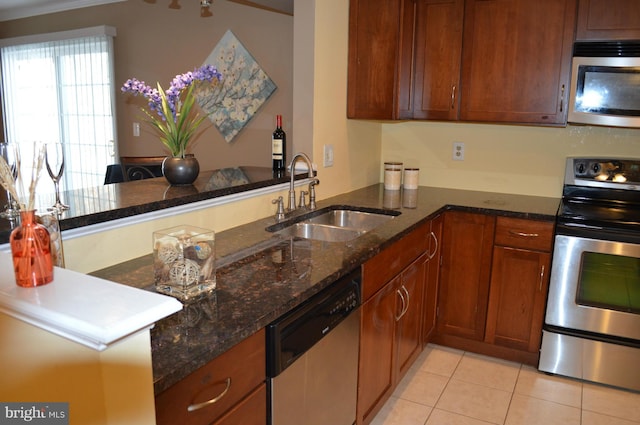 kitchen with a peninsula, appliances with stainless steel finishes, dark stone countertops, and a sink