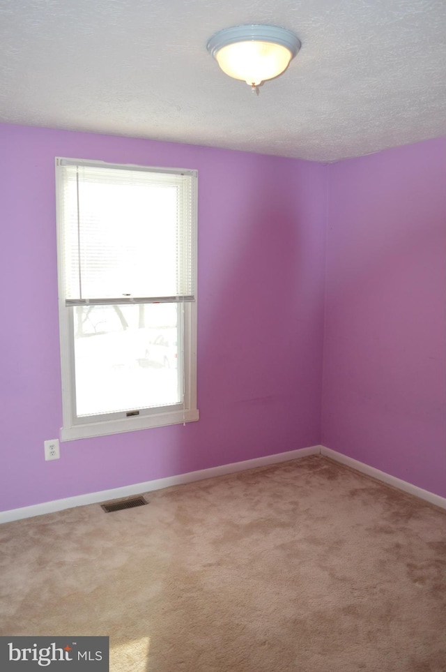 unfurnished room with baseboards, visible vents, a textured ceiling, and carpet flooring