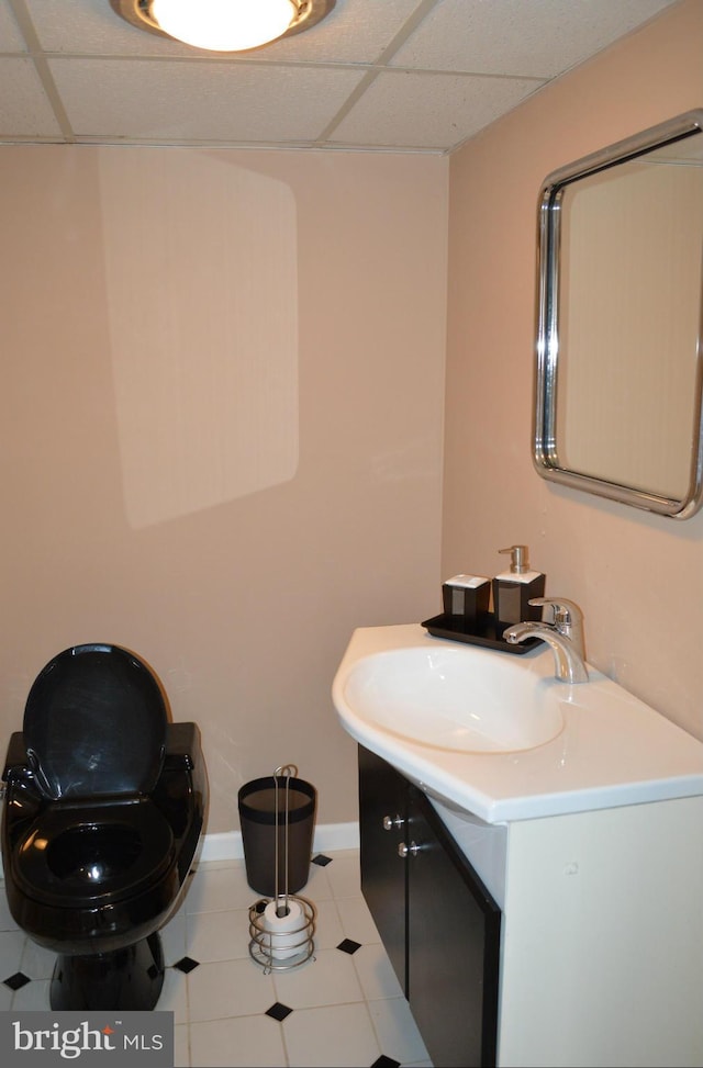 bathroom featuring a paneled ceiling, baseboards, and vanity