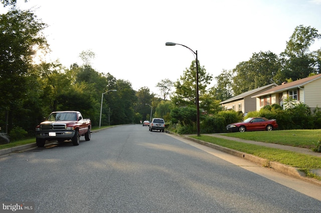 view of road featuring street lights, curbs, and sidewalks