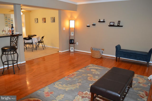 sitting room featuring ornamental molding, ceiling fan, baseboards, and wood finished floors