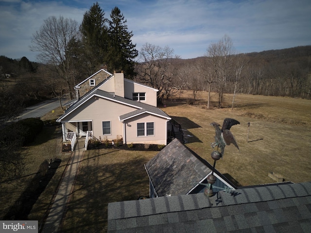 view of side of property featuring a chimney, a porch, and a lawn