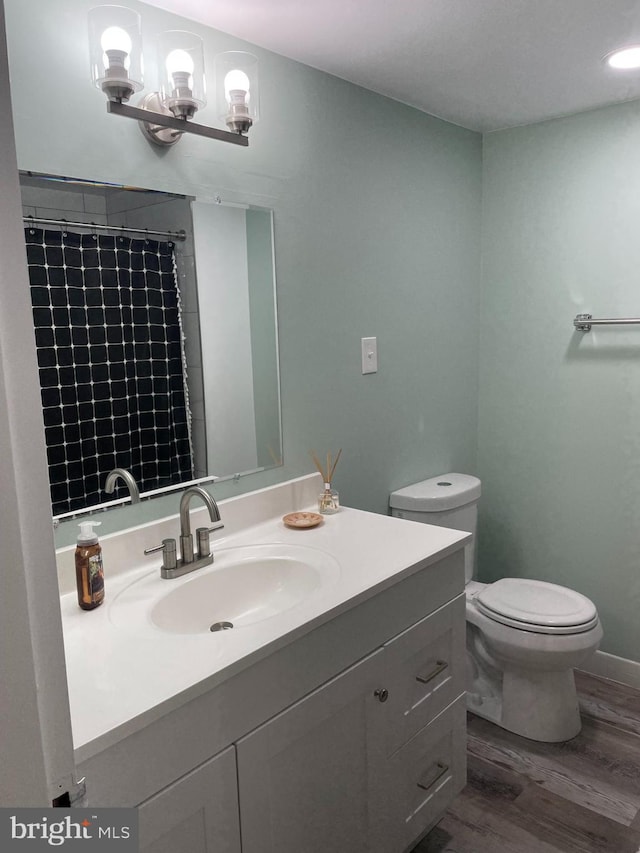 full bath with curtained shower, toilet, wood finished floors, vanity, and an inviting chandelier