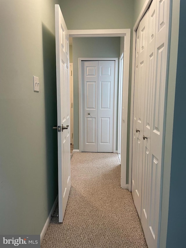 hall featuring light carpet and baseboards