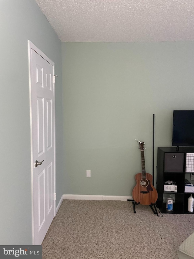 interior space with carpet, baseboards, and a textured ceiling