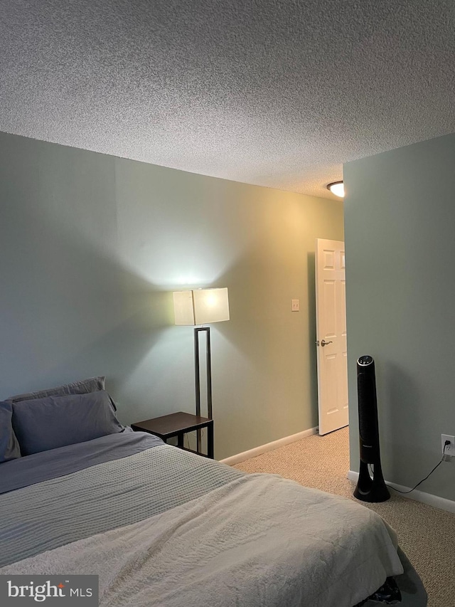 bedroom featuring carpet, baseboards, and a textured ceiling