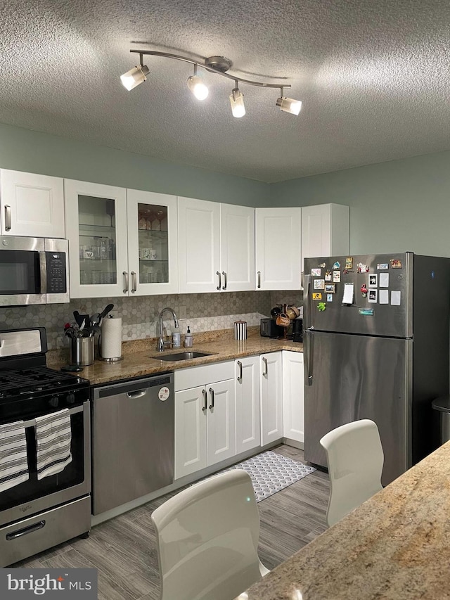 kitchen featuring white cabinets, light wood-style flooring, stainless steel appliances, and a sink