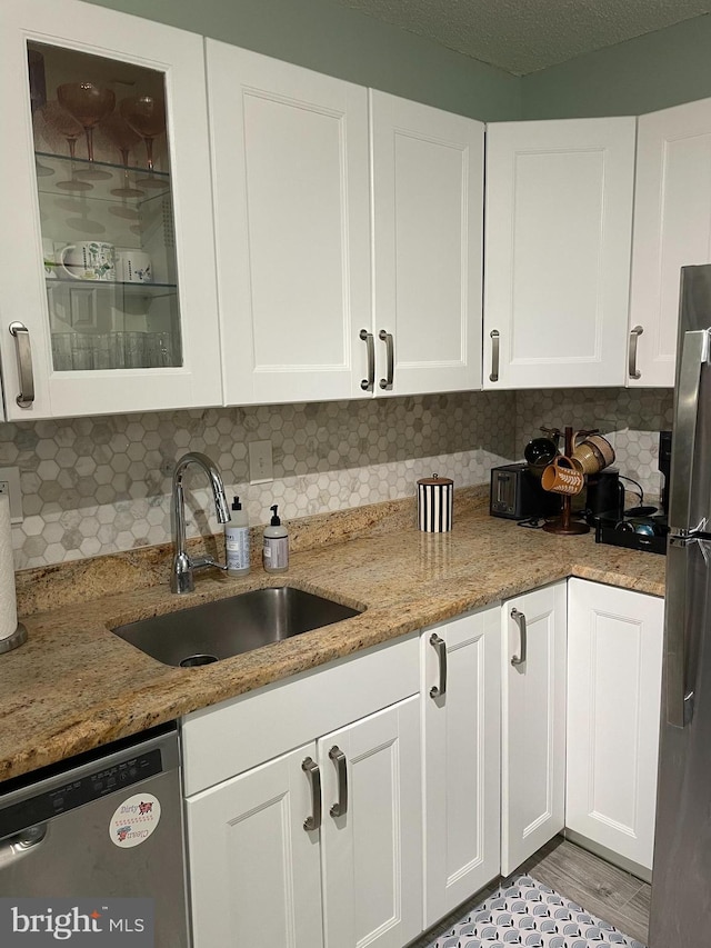 kitchen with white cabinets, decorative backsplash, stainless steel appliances, and a sink