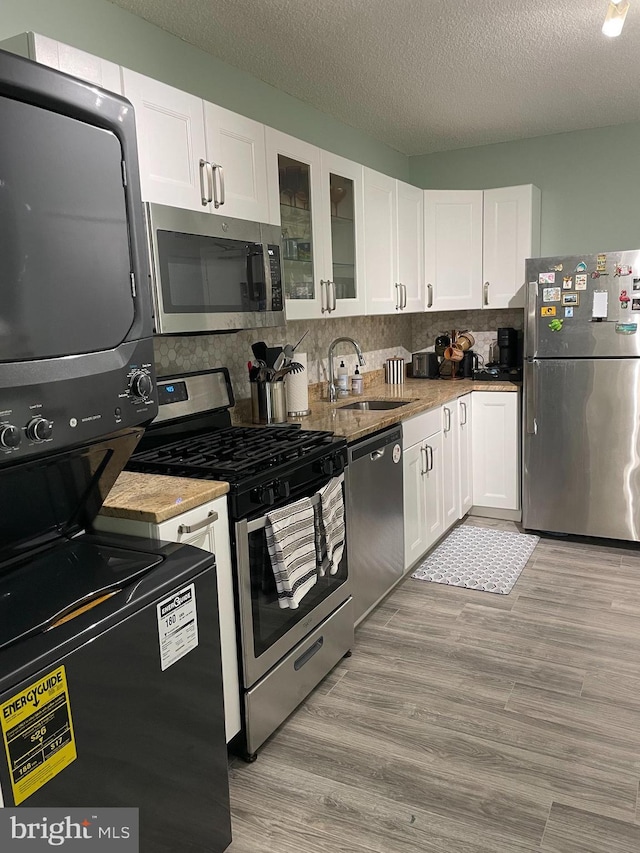 kitchen with white cabinets, light wood-style flooring, stainless steel appliances, and a sink