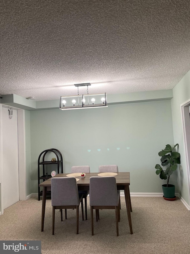 carpeted dining space with a textured ceiling and baseboards