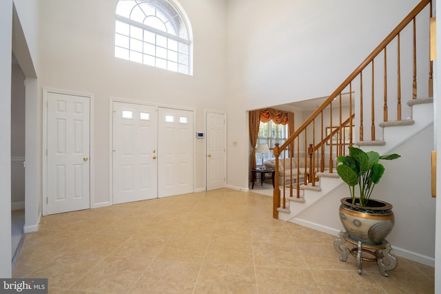 entrance foyer featuring stairs, a high ceiling, and baseboards