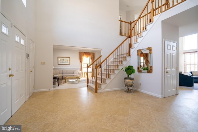 foyer entrance with baseboards, stairs, and a high ceiling