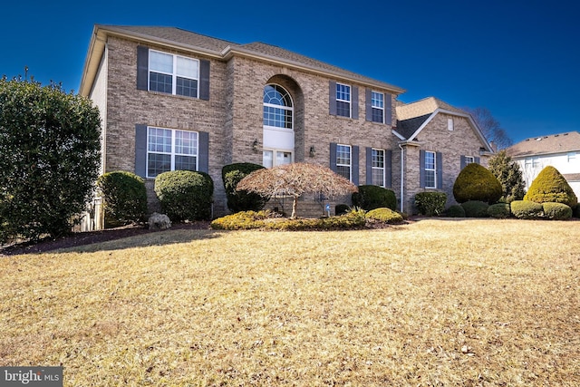 traditional-style house featuring a front yard and brick siding