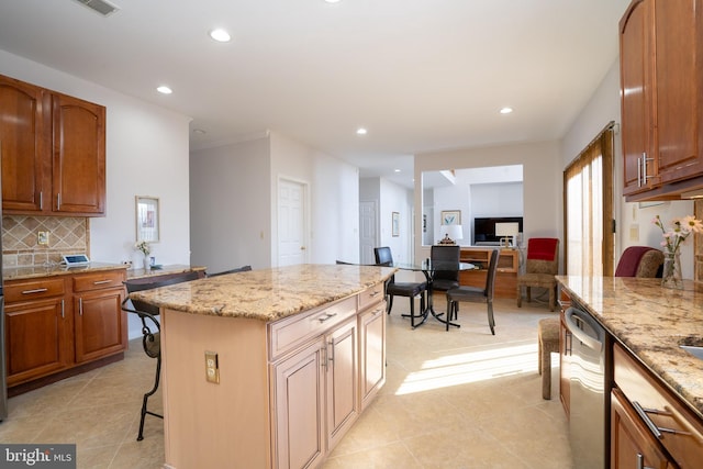 kitchen featuring a kitchen island, a breakfast bar area, light stone counters, and stainless steel dishwasher