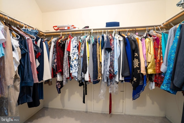 walk in closet with vaulted ceiling and carpet flooring