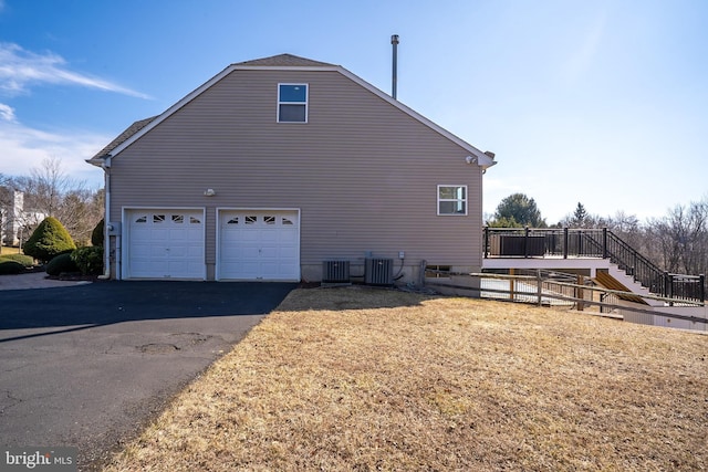 view of home's exterior with stairs, driveway, an attached garage, and central AC unit