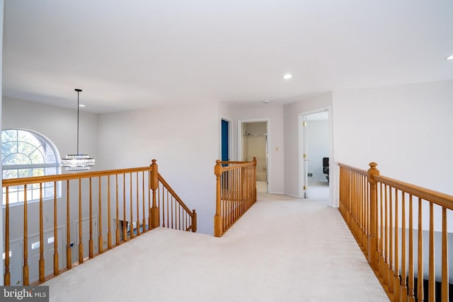 corridor featuring a notable chandelier, light colored carpet, an upstairs landing, and recessed lighting