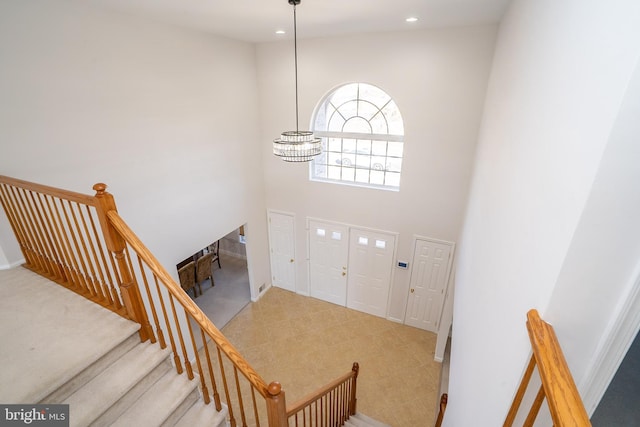 foyer entrance featuring a chandelier, recessed lighting, stairway, and a high ceiling