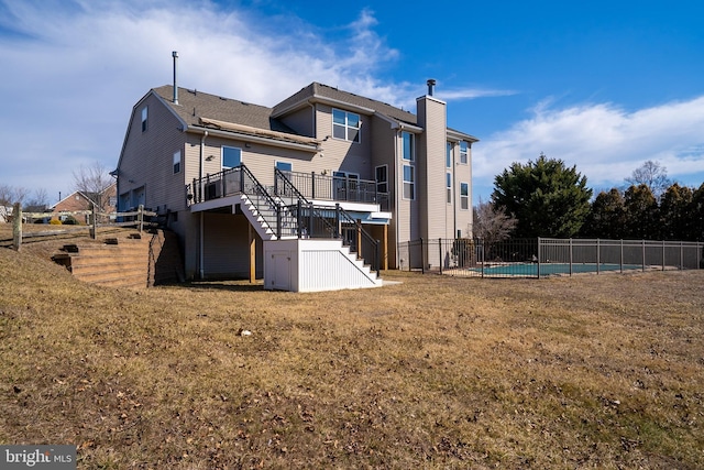 back of house featuring a yard, stairs, a fenced in pool, and a wooden deck