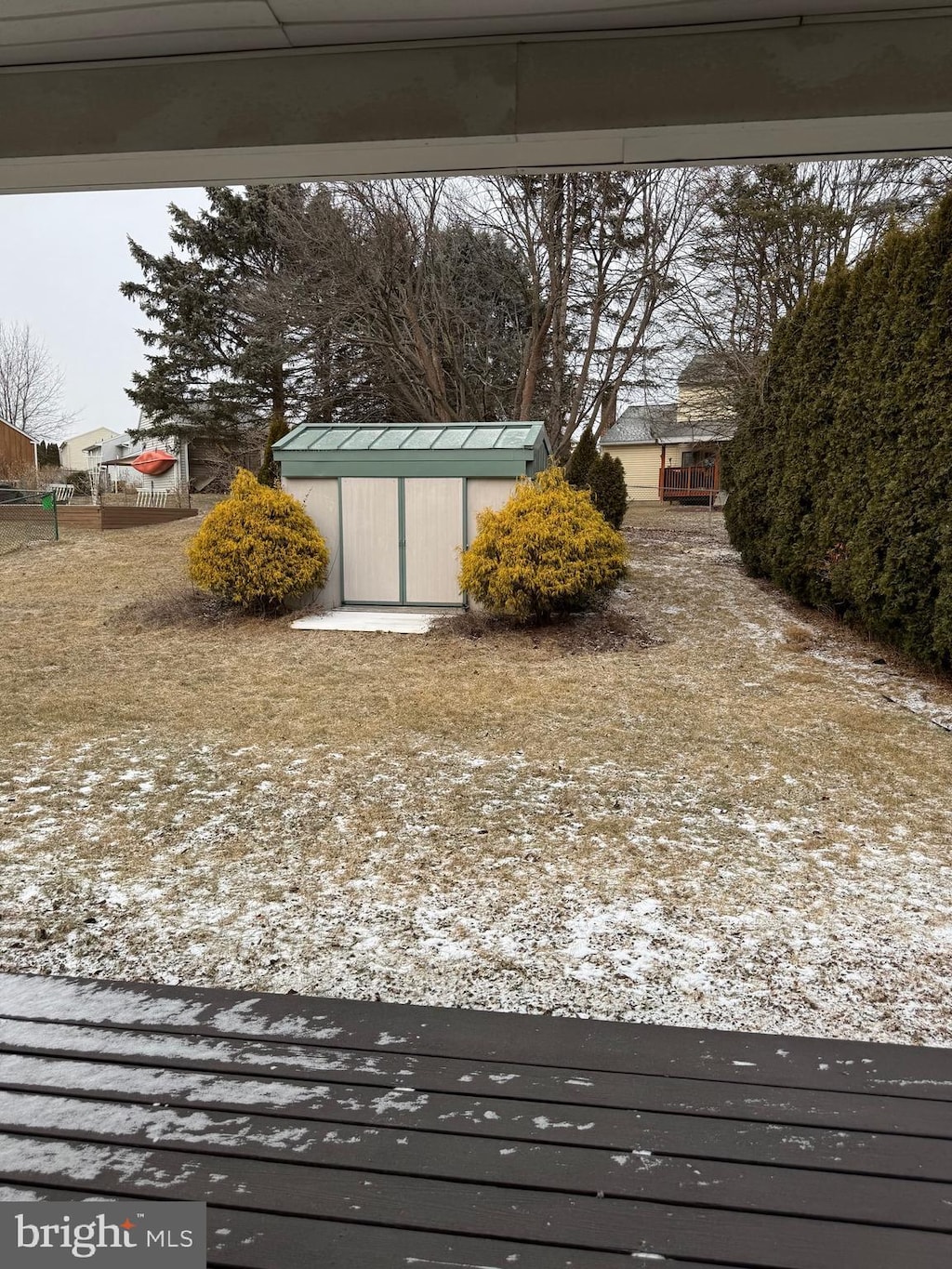 snowy yard with an outbuilding, fence, and a storage shed