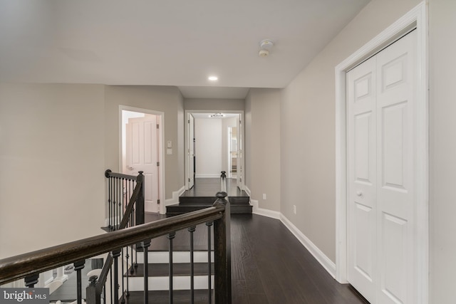 corridor with recessed lighting, baseboards, dark wood-style flooring, and an upstairs landing