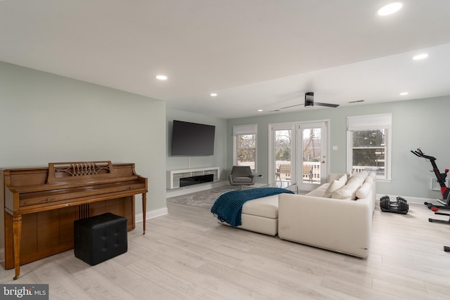 living area featuring recessed lighting, baseboards, a tiled fireplace, and light wood finished floors