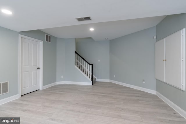 below grade area featuring light wood-style floors, visible vents, and stairway