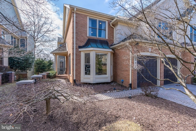 rear view of house with a garage, driveway, and brick siding