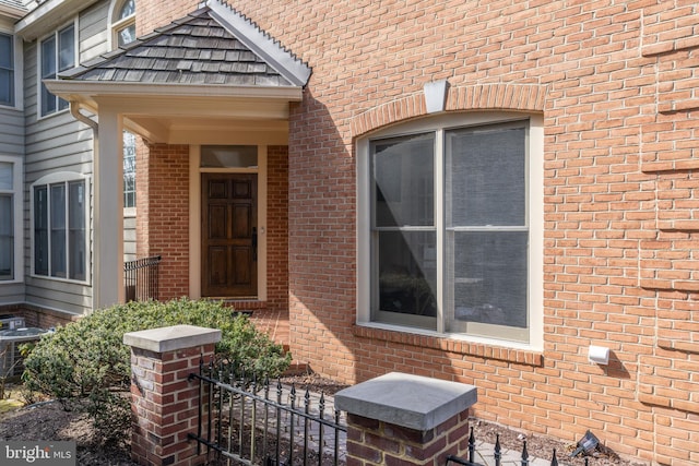 property entrance with central AC, brick siding, and fence