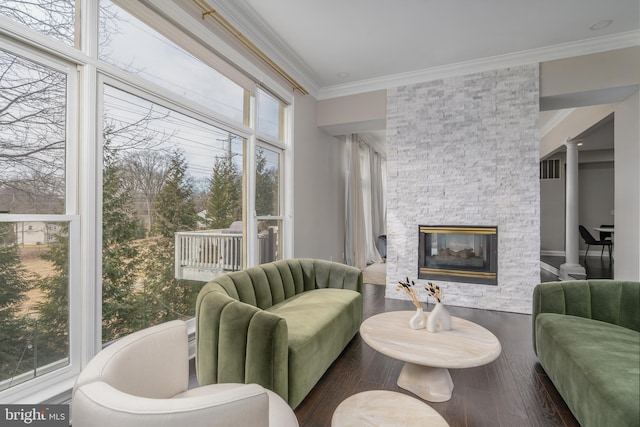 living area featuring a fireplace, crown molding, visible vents, wood finished floors, and ornate columns