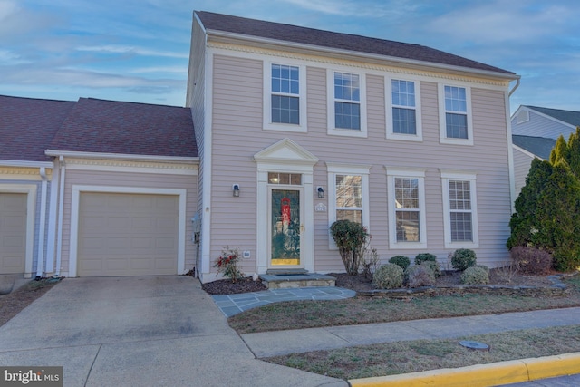 colonial home featuring a garage, driveway, and a shingled roof