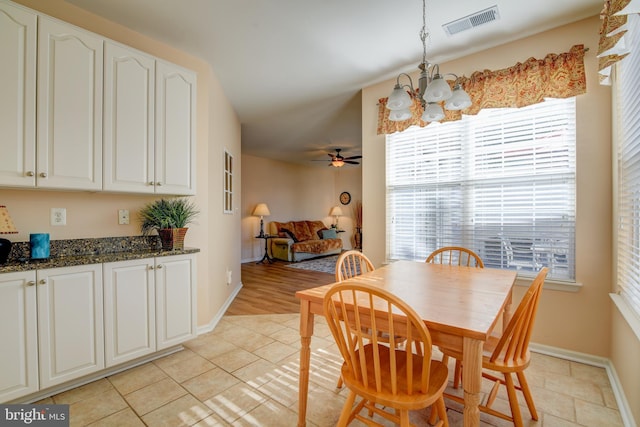 dining area featuring ceiling fan with notable chandelier, light tile patterned floors, visible vents, and baseboards